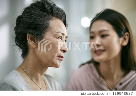 young asian daughter comforting elderly mother young asian daughter comforting elderly mother 119948687