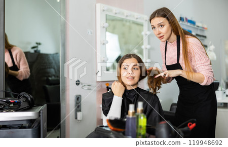 Young woman explains to the hairdresser how she wants to get a haircut Young woman explains to the hairdresser how she wants to get a haircut 119948692