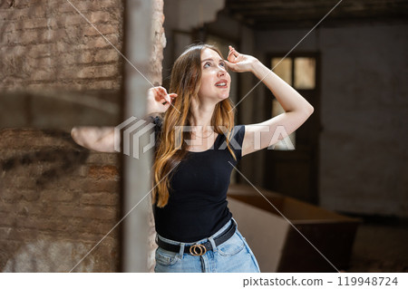 Young woman in jeans and black t-shirt posing inside ruined house 119948724