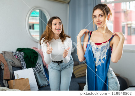 Two young women choosing clothes to wear Two young women choosing clothes to wear 119948802