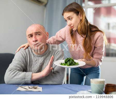 Woman serving salad for her displeased husband 119948806