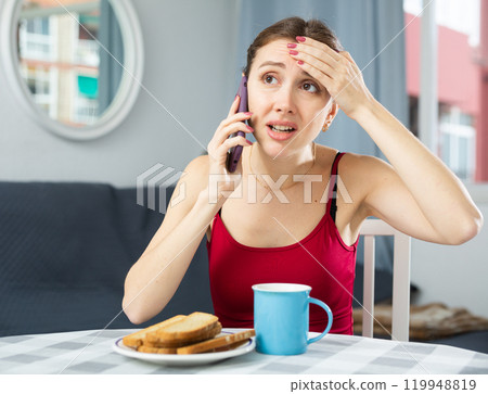 Caucasian woman having fever sitting and talking on phone Caucasian woman having fever sitting and talking on phone 119948819