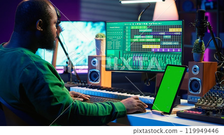 Songwriter composer mixing and mastering tracks next to green screen, operating on digital audio pc interface to add sound effects on new recordings. Technician in home studio. Camera A. 119949446