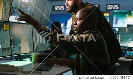 Army telecommunications operators using radio and satellite gear, inputting data on systems. Military dispatchers managing communications networks, typing on keyboard, camera A 119949477