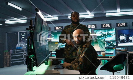Soldier doing tasks in military base, doing surveillance with digital radar equipment, operating missile systems. Middle Eastern man monitoring army HQ CCTV for any unauthorized activity, camera B 119949481