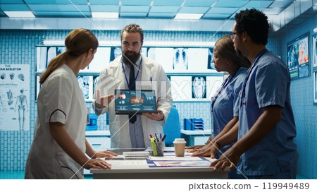 Skilled team of medics examine x ray scans and discuss health care plans during a research meeting. Diverse healthcare staff working to provide accurate diagnostics in a private clinic. Camera B. 119949489