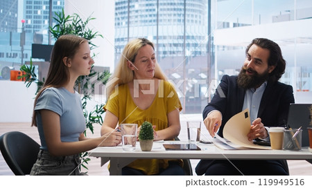 Financial advisor meeting with clients to counsel them on their finances, making list of steps to achieve comfortable income. Agent creating budget for customers, giving investing advice, camera A 119949516