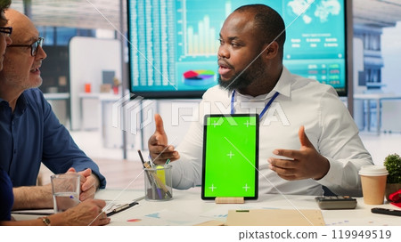 Adviser shows green screen on a tablet to middle aged people in modern office, meeting to discuss retirement and pension plan. Financial expert broker helping senior couple with finances. Camera A. Adviser shows green screen on a tablet to middle aged people in modern office, meeting to discuss retirement and pension plan. Financial expert broker helping senior couple with finances. Camera A. 119949519
