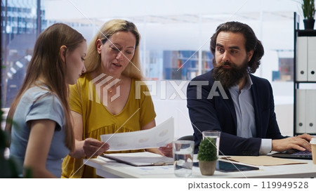 Financial advisor in office with mother and gen Z girl to provide personalized spending plan. Agent evaluating clients financial needs, performing analysis during business meeting, camera B Financial advisor in office with mother and gen Z girl to provide personalized spending plan. Agent evaluating clients financial needs, performing analysis during business meeting, camera B 119949528