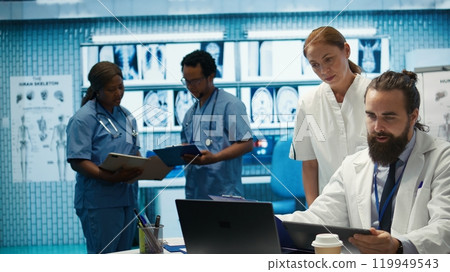 Healthcare professionals examine human anatomy scans to develop treatment plans, teamwork and expertise in radiology. Medical specialists work on analytics at private facility. Camera B. Healthcare professionals examine human anatomy scans to develop treatment plans, teamwork and expertise in radiology. Medical specialists work on analytics at private facility. Camera B. 119949543