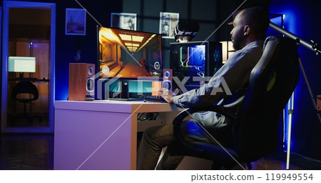 Man arriving at home to play videogames on gaming PC at computer desk, enjoying day off from work. Gamer entering room, battling enemies in online multiplayer shooter, camera B 119949554