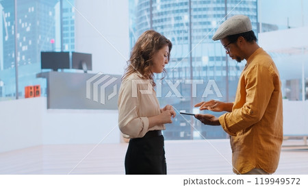 Property broker presenting real estate investment opportunity to client, reviewing blueprints layouts on tablet for leasing contract. Agent discussing architectural design for relocation. Camera B. Property broker presenting real estate investment opportunity to client, reviewing blueprints layouts on tablet for leasing contract. Agent discussing architectural design for relocation. Camera B. 119949572