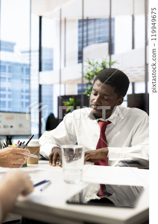 HR worker reviewing candidate, asking questions about qualifications, giving him contract to read. Man at interview checking paperwork after proving skills and enthusiasm for job opportunity 119949675