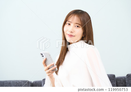 Young woman in plain clothes, living room, smartphone Young woman in plain clothes, living room, smartphone 119950753