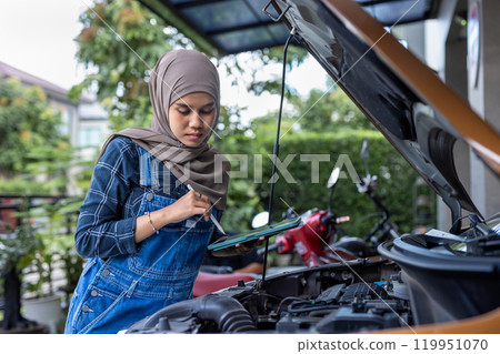Asian muslim wear hijab woman using tablet checking up automobile engine before departure. Female trying fix their car to motor mechanic. 119951070