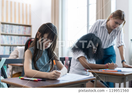 School children education in classroom. kid schoolgirl happy learning. Writing as instructed by teacher. concept of back to school. 119951560