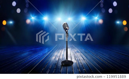 A stand microphone set up on a stage illuminated by blue lights Image of a concert 119951889