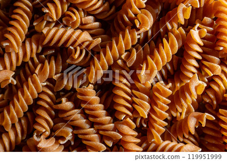 Uncooked Whole Grain Fusilli Pasta Background Uncooked Whole Grain Fusilli Pasta Background 119951999