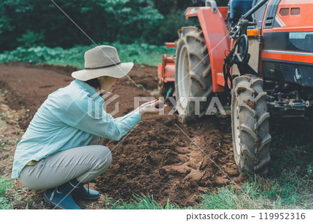 Woman looking at soil in a field 119952316