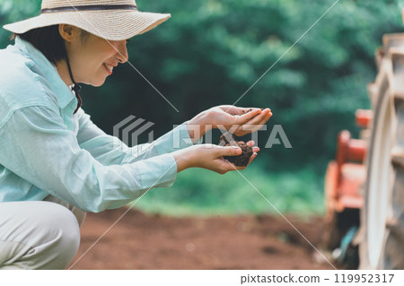 Woman looking at soil in a field 119952317