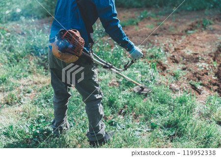 A man mowing the grass with an engine-powered lawnmower A man mowing the grass with an engine-powered lawnmower 119952338