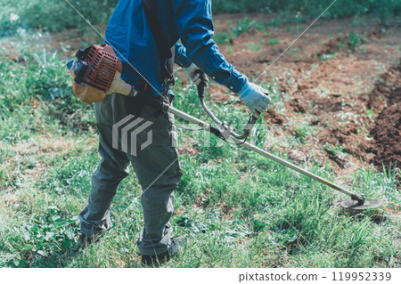 A man mowing the grass with an engine-powered lawnmower A man mowing the grass with an engine-powered lawnmower 119952339