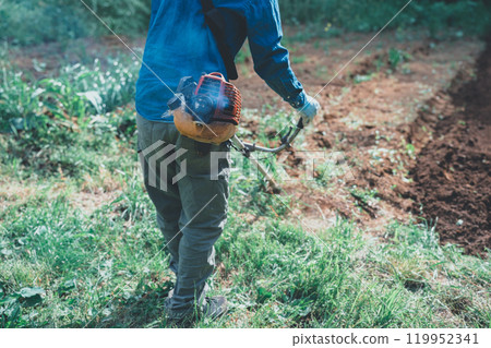 A man mowing the grass with an engine-powered lawnmower 119952341