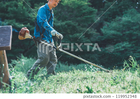 Man mowing the grass with a lawnmower Man mowing the grass with a lawnmower 119952348