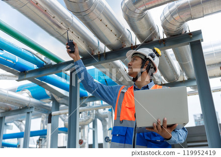 Man Industrial engineer with walkie talkie pointing work at rooftop construction. Male technician working checking HVAC system building factory. Installing large air conditioning system. 119952419