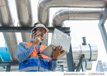 Asian man engineer using talkie walkie report working at rooftop building construction. Technician worker working checking hvac of office building. Engineering installing air conditioning system. 119952420