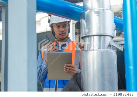 Male operator worker walkie talkie using laptop checking quality cooling air piping HVAC system at industrial building. Man engineer working Heating Ventilation and Air conditioning system. 119952482