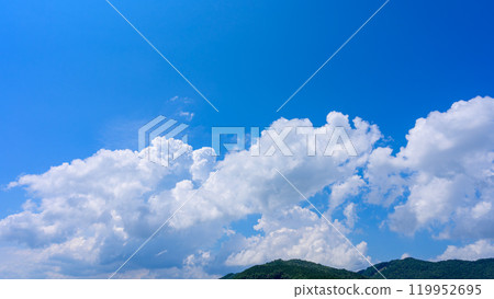 在夏日藍色的天空下,許多白雲在山頂上流動 在夏日藍色的天空下,許多白雲在山頂上流動 119952695