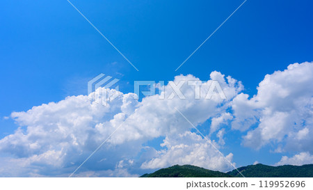 在夏日藍色的天空下,許多白雲在山頂上流動 在夏日藍色的天空下,許多白雲在山頂上流動 119952696