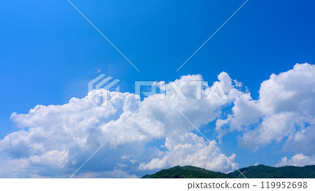 在夏日藍色的天空下,許多白雲在山頂上流動 在夏日藍色的天空下,許多白雲在山頂上流動 119952698