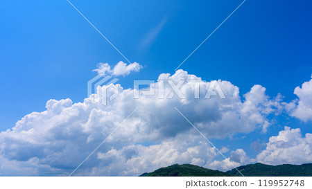 在夏日藍色的天空下，許多白雲在山頂上流動 119952748