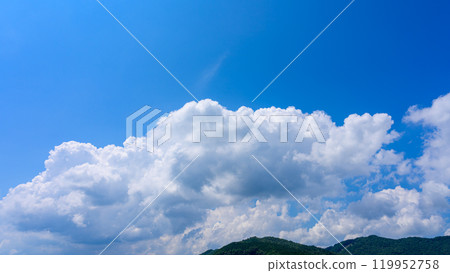 在夏日藍色的天空下,許多白雲在山頂上流動 在夏日藍色的天空下,許多白雲在山頂上流動 119952758