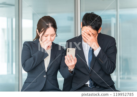 An office worker who is shocked when he sees his smartphone/smartphone (flame, trouble, failure, harassment, trouble) 119952785