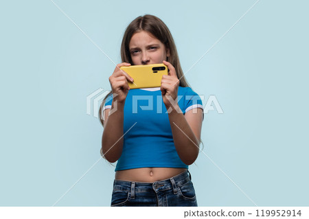 Girl concentrating intensely while holding smartphone 119952914