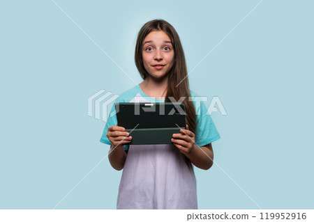 Girl holding tablet, making quirky face 119952916