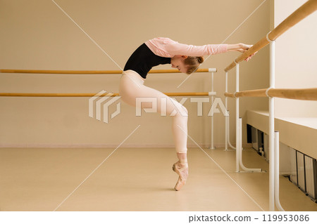 Ballet dancer performing deep backbend at barre, balancing on pointe Ballet dancer performing deep backbend at barre, balancing on pointe 119953086