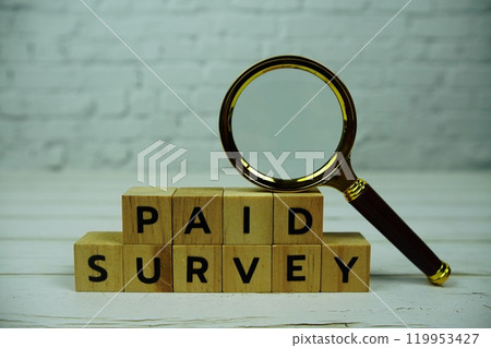 Paid Survey with wooden blocks alphabet letters and magnifying glass on wooden background 119953427