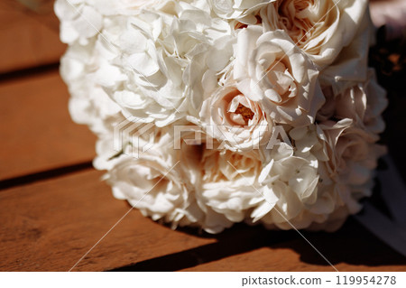 A wedding bouquet of white flowers sits on a wooden table A wedding bouquet of white flowers sits on a wooden table 119954278