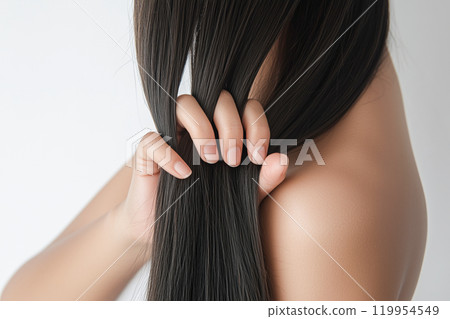 Close-up of a young woman grabbing her hair with her hands. Close-up of a young woman grabbing her hair with her hands. 119954549
