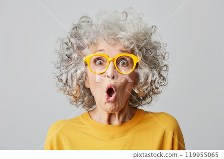 Joyful very surprised 70 year old American woman with big amazed eyes and surprised mouth, with intense makeup, red lips, hair styling and rose-colored glasses. Live emotions. Idea for advertising 119955065