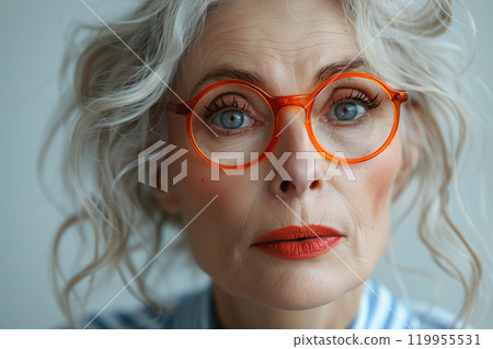 An elegant elderly lady with a modern hairstyle and soft blue eyes. The look is filled with confidence and inner peace. Concept of a successful and stylish woman. Classic atmosphere and modern style. 119955531