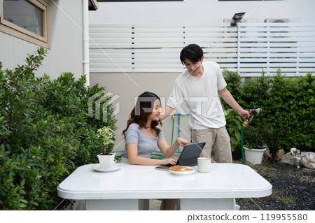 Cheerful asian couple enjoys a relaxing day in cozy backyard Cheerful asian couple enjoys a relaxing day in cozy backyard 119955580