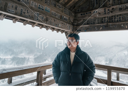 man tourist sightseeing view of village with snow in winter from mountain viewpoint of Yamadera temple or Risshakuji temple located in Yamagata City, in Yamagata Prefecture, Tohuku, Japan 119955870
