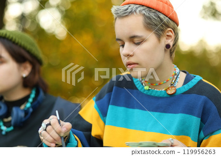Creative Spirit. The Young Artist in Nature. a young female artist passionately painting outdoors, with brushes and paints in her hands. Surrounded by the beauty of nature, she is fully immersed in Creative Spirit. The Young Artist in Nature. a young female artist passionately painting outdoors, with brushes and paints in her hands. Surrounded by the beauty of nature, she is fully immersed in 119956263
