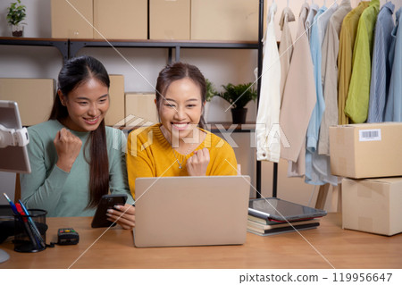 Two young asian woman using tablet and laptop computer for looking review of store in office. 119956647