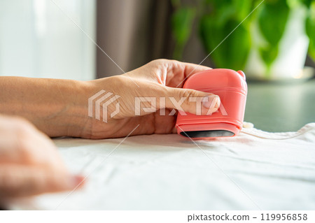 Close-up view of woman's hands with a stamp with a name for signing children's things. Identification of personal clothing. 119956858